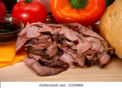 Makings Of A Roast Beef Sandwich Including California Sourdough, Deli Sliced Angus Roast Beef, Tomato, Cheddar Cheese, Au Ju Sauce, Peppers