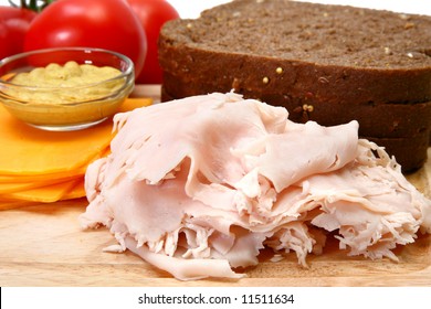 Makings Of A Turkey Sandwich Includeing Dark German Wheat, Sliced Turkey, Tomatoe, Spicey Mustard, Cheddar Cheese.