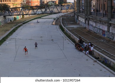 MALAGA, ANDALUSIA, SPAIN - JULY 25, 2017: Two players are playing footvolley (combines soccer and volleyball) with their feet in front of a small audience at the dried riverbank of Guadalmedina river.