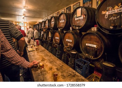 MALAGA, SPAIN: Drinkers meeting, having fun, drinking sweet wine with ice, inside old spanish bar with local wine barrels on November 24, 2018. Andalusian city Malaga has population of 600,000 people