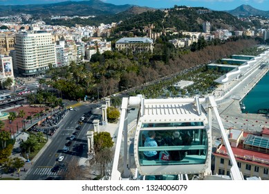 
Malaga, Spain, February 2019. People Visiting The Spanish City Of Malaga From The Cab Of The Ferris Wheel. Travel Older Couples. Beautiful Landscape: City, Mountains, Houses Against The Blue Sky.