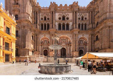 Malaga, Spain, June 10, 2022; Facade Of The Malaga Cathedral Or Santa Iglesia Catedral Basílica De La Encarnación, With A Fountain And Tourists In The Town Square In The Foreground.