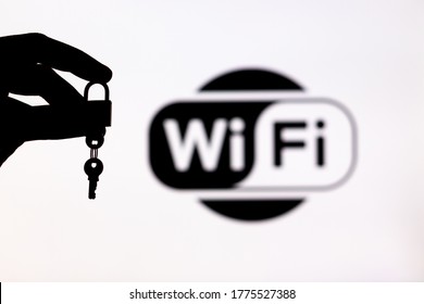 Malaga, Spain - May 18th, 2020: WIFi Security. Hand Holding A Locked Padlock With A Key Besides A WiFi Logo