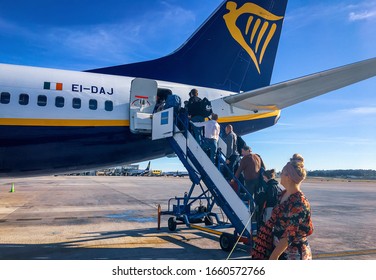 Malaga/Spain, Dec. 23, 2019.
Group of people entering a RyanAir flight by stairs at the Malaga Airport, through the rear entrance. It a sunny day with peolple lightly dressed.