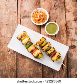 Malai Paneer Tikka Kabab - is an Indian dish made from chunks of cottage cheese marinated in spices, cream & grilled in a tandoor. Served in a plate with salad & green mint chutney. Selective focus