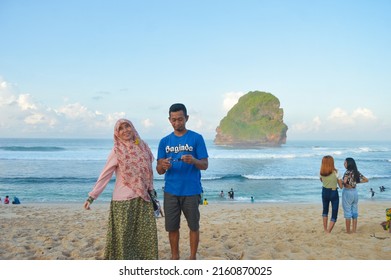 Malang, Indonesia - May 7 2022: photo of a family traveling during the Ramadan holiday on the coast of Goa Cina, Malang City, Indonesia