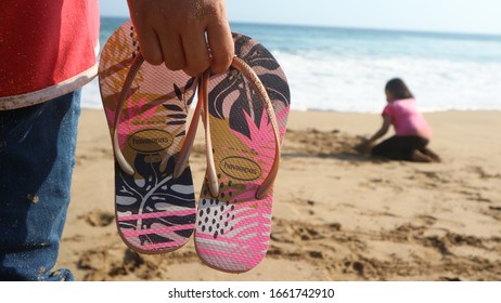 MALANG, INDONESIA - SEPTEMBER 24, 2019: A Beach Visitor Brings Havaianas Sandals