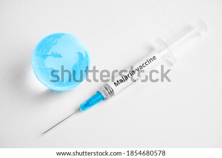 Malaria vaccine concept in syringe with world map on globe.