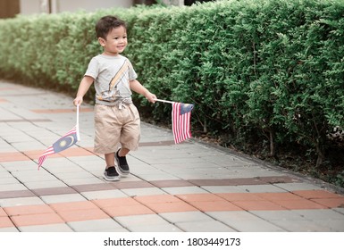 Malay Baby Boy Holding A Malaysian Flag With A Clean Outdoor Background