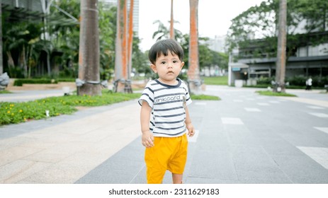 A Malay baby boy wearing stripes shirt and yellow short pants - Shutterstock ID 2311629183