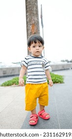 A Malay baby boy wearing stripes shirt and yellow short pants - Shutterstock ID 2311629193