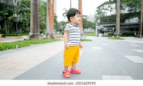 A Malay baby boy wearing stripes shirt and yellow short pants - Shutterstock ID 2311629195