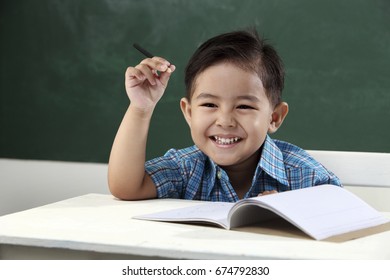 Malay Boy Sitting In The Classroom Holding Pencil