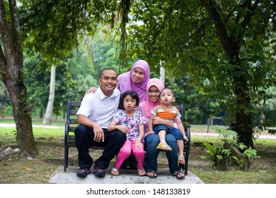 Malay Family Sitting And Having Fun In The Park