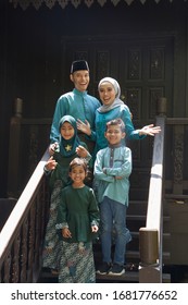 Malay Family Standing At Front Yard Wavingwith Welcome Gesture