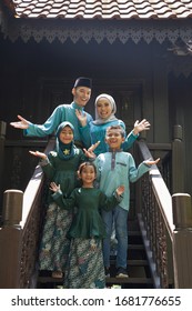 Malay Family Standing At Front Yard Wavingwith Welcome Gesture