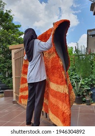 A Malay Girl With Black Hijab Hanging And Drying A Heavy Carpet On The Steel Gate. Cleaning And Drying. Remove Dust. Under The Hot Sun. Brown Tiles Floor. Malaysia. March 2021