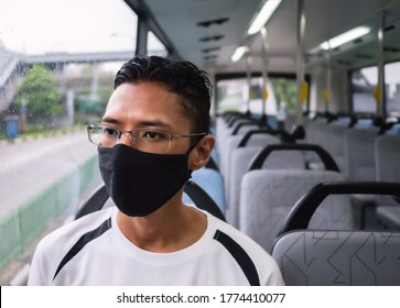 A Malay  Southeast Asian Man Wearing A Black Face Mask Sits Alone In A Bus In Singapore.