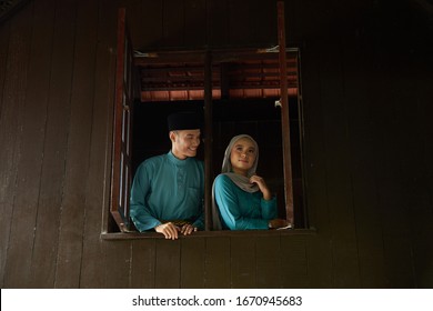 Malay Young Couple At The Wooden Window Of A Traditional Malay House