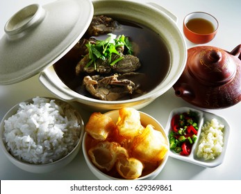 Malaysia food-Bah kut teh,a teapot of chinese tea,a cup of chinese tea,A bowl of chopped yau char kway,a bowl of rice,chillies and garlic 
