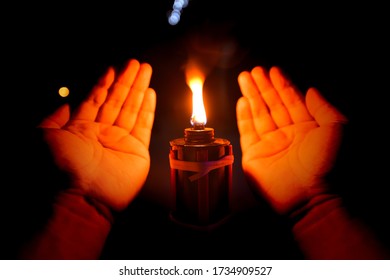 Malaysia Traditional Celebratory Oil Lamps Burning In Low Lighting (Lampu Pelita) With Praying Hand On Selective Focus Point