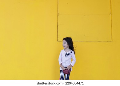 Malaysian Girl Children With Excited Facial Expression Over Plain Yellow Background Copyspace