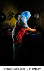 Malaysian lady using natural sunlight to prepare food in the kitchen.
