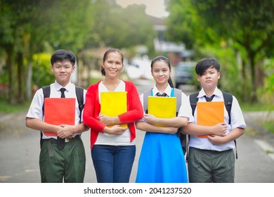 Malaysian Secondary Students With Teacher Outdoor Portrait.Male And Female Young Teens In Malaysia Wearing School Uniform In School While Holding Book And Backpack.Education In Asia.