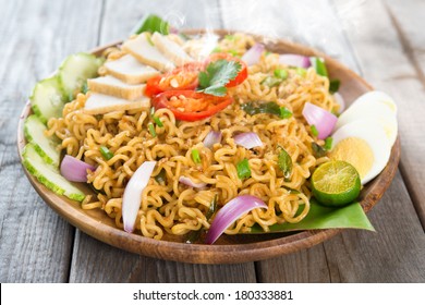 Malaysian Style Maggi Goreng Mamak  Or Spicy Fried Curry Instant Noodles.  Asian Cuisine, Ready To Serve On Wooden Dining Table Setting. Fresh Hot With Steamed Smoke.