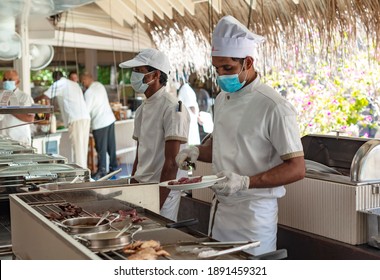 Maldives - December 2020: Chefs And Hotel Workers Work At The Buffet In A New Reality In Protective Face Masks And With A Protective Screen Due To The Coronavirus Pandemic In The World