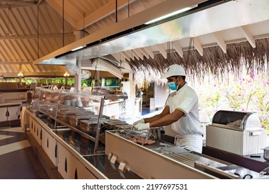 Maldives - December 2020: Chefs And Hotel Workers Work At The Buffet In A New Reality In Protective Face Masks And With A Protective Screen Due To The Coronavirus Pandemic In The World