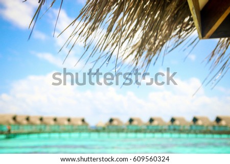 Maldives resort's lagoon water villa and deep blue sea, sky. Blurry background.