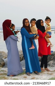 MALDIVES – THULUSDHOO – JANUARY 2020 -  Triplets Maldivian Covered Women With Their Children Watching The Sunset On The Island.