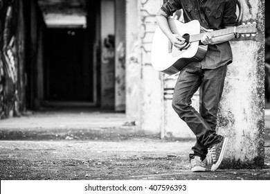Мужчина с акустической гитарой на открытом воздухе, черно-белое фото