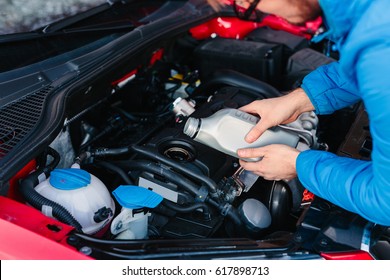 Male Adding Oil Under The Hood Of The Car. DIY Oil Change.