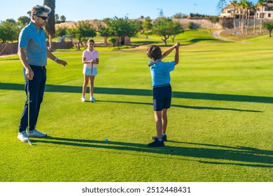 Male adult caucasian golf instructor guiding a boy and a girl playing golf in a green course outdoors - Powered by Shutterstock