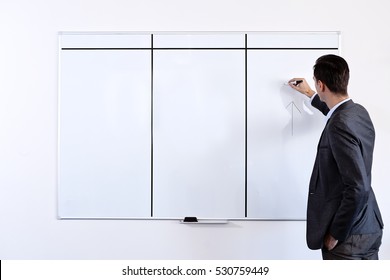 Male Adult Man In A Suit Standing And Writing On A White Board In A Office During Presentation