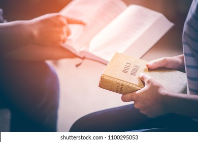 Male adults are reading the Holy bible by pointing to the character and to share the gospel to youth. The cross symbol, glow over the books of the Bible, Concepts of Christianity.
