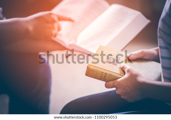 Male adults are\
reading the Holy bible by pointing to the character and to share\
the gospel to youth. The cross symbol, glow over the books of the\
Bible, Concepts of\
Christianity.