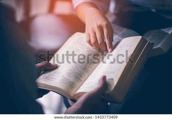 Male adults are reading\
the Holy bible by pointing to the character and to share the gospel\
to youth. The cross symbol, The books of the Bible, Concepts of\
Christianity.