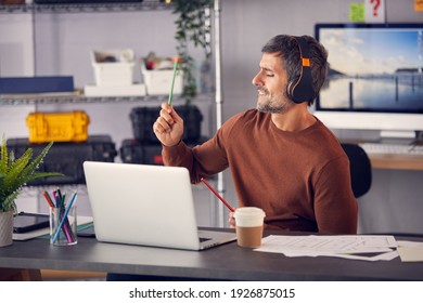 Male Advertising Marketing Or Design Creative With Wireless Headphones Air Drumming At Desk