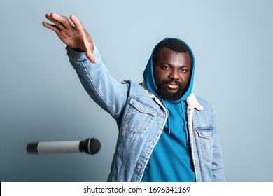 Male African-American singer dropping microphone on color background