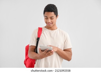 Male African-American student with tablet computer and backpack on light background - Powered by Shutterstock