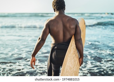 Male afro surfer having fun surfing during sunset time - African man enjoying surf day - Extreme sport lifestyle people concept  - Powered by Shutterstock