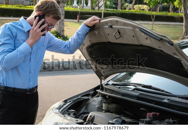 male agent examining engine for claiming auto\
insurance. caucasian man calling for assistance for car broken down\
by traffic accident