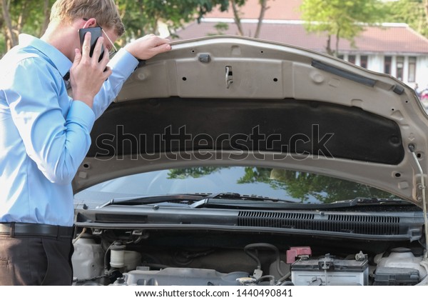male agent examining engine for claiming auto\
insurance. caucasian man calling for assistance for car broken down\
by traffic accident