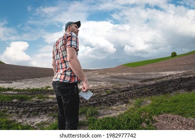 A male agronomist examines the fields after heavy rains against the backdrop of rainy clouds. Weather damage assessment agricultural land after flood - Powered by Shutterstock