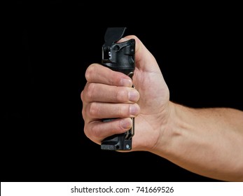 male aiming pepper spray on black background