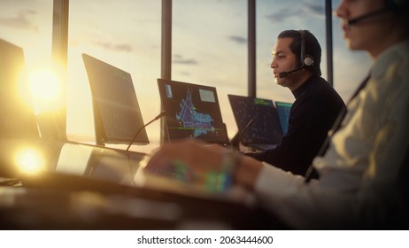 Male Air Traffic Controller With Headset Talk On A Call In Airport Tower. Office Room Is Full Of Desktop Computer Displays With Navigation Screens, Airplane Departure And Arrival Data For The Team.