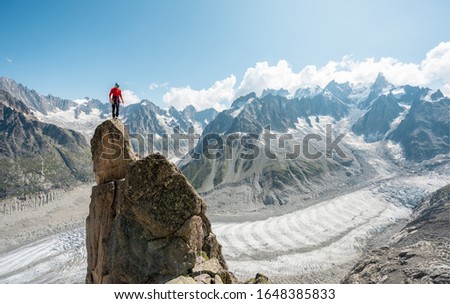 Male alpinist standing up on top of the mountain peak